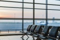 View of airport interoir, empty bench chairs in the departure hall during sunrise. Airplane and building background Royalty Free Stock Photo