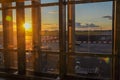 View from the airport window of the airfield with planes and maintenance vehicles at sunset