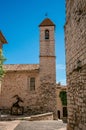 View alley and church with stone steeple tower in Saint-Paul-de-Vence.