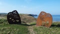 View along a coastal path with clear blye sky showing public art sculture, cliffs, sea and blue sky