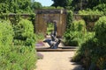 A view along the gravel path, past a statue of a girl and swan and onwards to the gateway of the kitchen garden in an old English Royalty Free Stock Photo