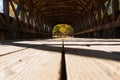 View along platform of Sunday River covered bridge with structure casting shadow pattern and leading lines