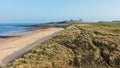 View along sand dunes towards the ruins of Dunstanburgh Castle. Royalty Free Stock Photo