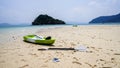 View along the shoreline, colourful kayaks paddle and sandals in foreground, National Park, Ranong, Thailand. Kayak on the beach