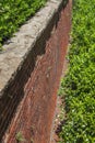 View alongside tall brick retaining wall with rusticated stone cap, green shrubbery Royalty Free Stock Photo