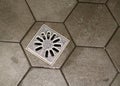 View of aluminium shower drain surrounded by hexagonal shaped tiled