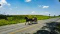 View of An Amish Horse and Open Buggy Traveling on a Rural Road Thru Farmlands