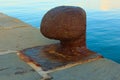 View of ancient and rusty marine ship mooring bollard on a dock by the waterÃ¯Â¿Â½s edge. Sunny morning in port of Koper, Slovenia