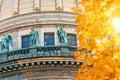 View of the ancient statues of stucco and the dome of St. Isaac`s Cathedral Petersburg autumn maple leaves. Royalty Free Stock Photo