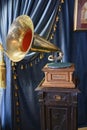 An antique gramophone on a carved wooden pedestal against the background of curtains with tassels. Inscription: \'Gramophone