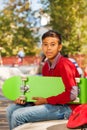 View of Arabian boy with green skateboard sitting Royalty Free Stock Photo