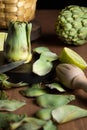 View of artichoke on table with peelings and limes, selective focus, on wooden table, black background