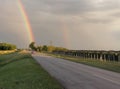 View of the asphalt road with cars and the rainbow above
