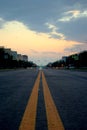 View of an asphalt road with yellow markings closeup and sunset sky in the background. Royalty Free Stock Photo