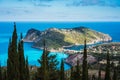 View to Assos village in sun light and beautiful blue sea. Cypress trees in foreground. Kefalonia island, Greece