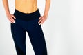 View of the athletic muscular belly and hips of a young woman in athletic tight-fitting trousers on a white background. Royalty Free Stock Photo