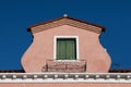 View of an atique window in an Italian house in Burano, Italy against a clear blue sky background Royalty Free Stock Photo