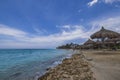 View of Atlantic ocean and beach with sun loungers and umbrellas against backdrop blue sky with white clouds. Royalty Free Stock Photo