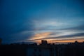 View on atmospheric sunset in blue, yellow and orange tones over sea and dark silhouettes of residential buildings. vertical Royalty Free Stock Photo