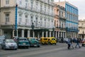 View of authentic Cuban Havana street with classic retro vintage cars parked near the buildings and people in background crossing Royalty Free Stock Photo