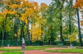 View of autumn trees, ancient marble statue, lawn and benches in