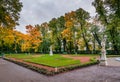 View of autumn trees, ancient marble statues and lawn in Summer