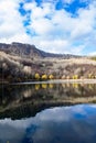 The view of autumn trees, the mountain, and the reflection of clouds in the lake. Royalty Free Stock Photo