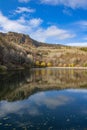 The view of autumn trees, the mountain, and the reflection of clouds in the lake. Royalty Free Stock Photo