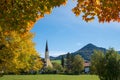 View through autumnal colored maple branches to saint leonhard church schliersee