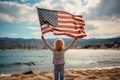 View from the back child holds the American flag of the USA on the background of the lake