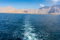 View from the back of a Dhow Boat looking to the Fjords, beautiful blue water, mountains and clouds of Musandam, Oman in the Royalty Free Stock Photo