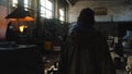 View from the back of man in protective coveralls and black cap going on the old steel making plant near melting furnace