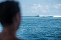 View from the back man surfer watching to the blue perfect waves from the boat