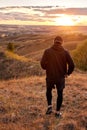 View from back on man walking in field after jogging, in sportive clothes