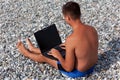 View from back of man working on notebook on beach Royalty Free Stock Photo