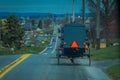 View of the back of an old fashioned, Amish buggy with a horse riding on gravel rural road Royalty Free Stock Photo