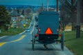 View of the back of an old fashioned, Amish buggy with a horse riding on gravel rural road Royalty Free Stock Photo