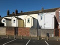 View of the back of a row of white and yellow painted typical small english terraced houses with parking spaces in fleetwood Royalty Free Stock Photo