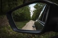 View back  to the gravel dirt road passing through dense forest in the rearviewmirror Royalty Free Stock Photo