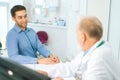 View from back of unrecognizable mature adult male doctor listening complaints of smiling patient during consultation at Royalty Free Stock Photo