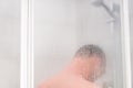 View from the back on a young man taking a shower behind misted Royalty Free Stock Photo