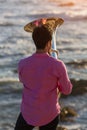 View from the back young musician play the trumpet on rocky sea coast during surf. Royalty Free Stock Photo