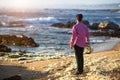 View from the back young musician play trumpet on rocky sea coast during surf. Royalty Free Stock Photo