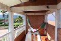 A hammock hanging in a narrow brick balcony with palm trees and hills behind it