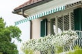 View of the balcony of the white house which is decorated with pots with white petunia