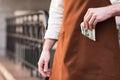 View of barista in brown apron putting money in pocket Royalty Free Stock Photo