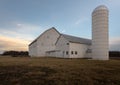 View of a barn and silo in the field at sunset Royalty Free Stock Photo