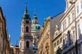 View of Baroque Church of Saint Nicholas, green dome and bell tower with clock, sunny winter day, snow on red roofs, Mala Strana Royalty Free Stock Photo