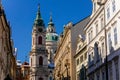 View of Baroque Church of Saint Nicholas, green dome and bell tower with clock, sunny winter day, snow on red roofs, Mala Strana Royalty Free Stock Photo