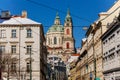 View of Baroque Church of Saint Nicholas, green dome and bell tower with clock, sunny winter day, snow on red roofs, Mala Strana Royalty Free Stock Photo